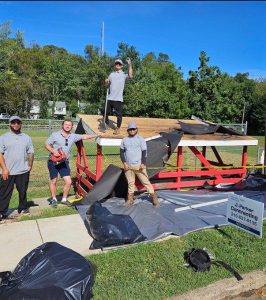 The J. Parker Contracting crew on a roof job, with the company sign in the foreground